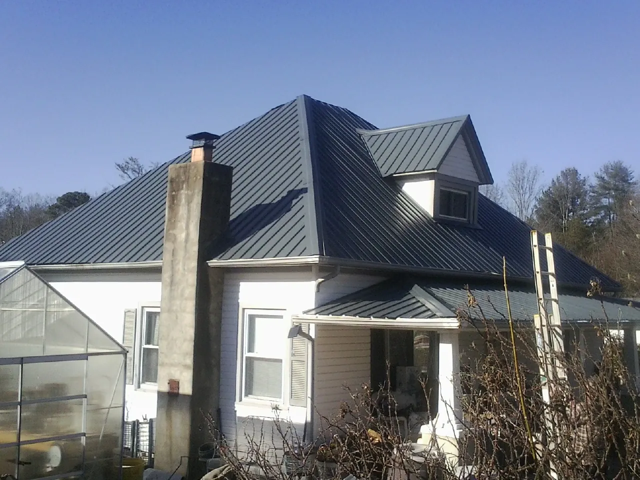 Dark blue standing seam metal roof on a white farmhouse with dormer — Slate & Tile Roof Repair by Roofing Brothers in Waldwick