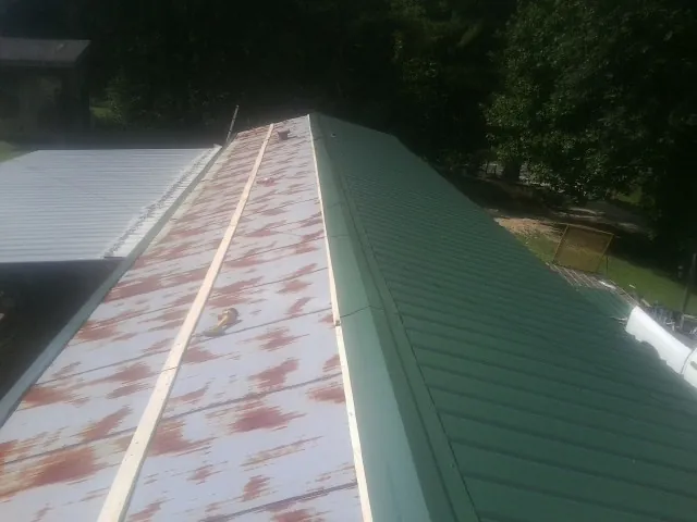 Old rusted panels beside newly installed green metal roofing — Wind Damage Roof Repair by Roofing Brothers in Waldwick