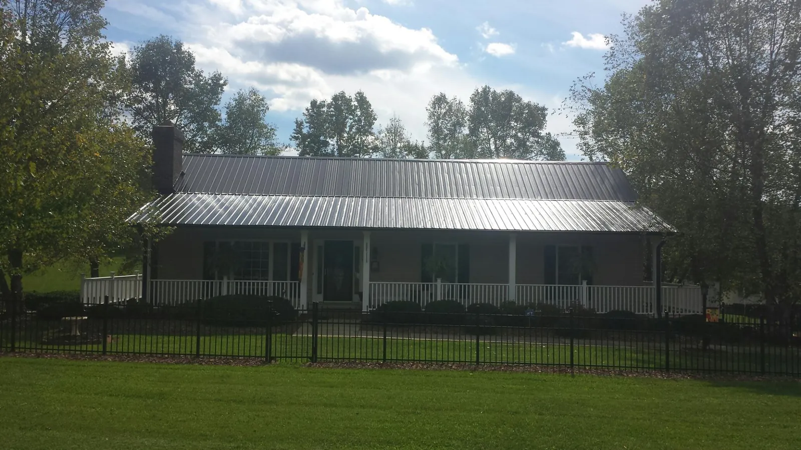 Gray metal roof on a brick ranch with a full width front porch — Gutter Guard Installation work by our crew in Waldwick