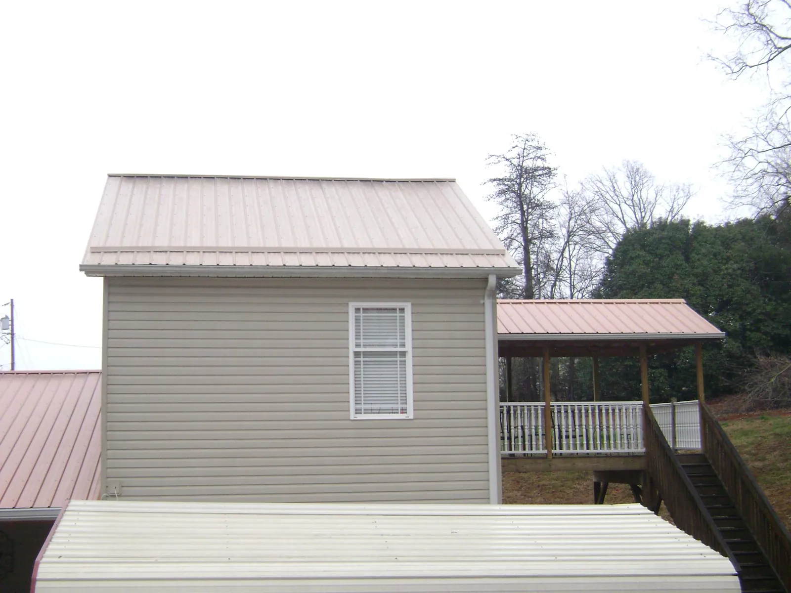Tan metal roofs on a two story addition and attached porch, from a Roof Replacement job in Waldwick