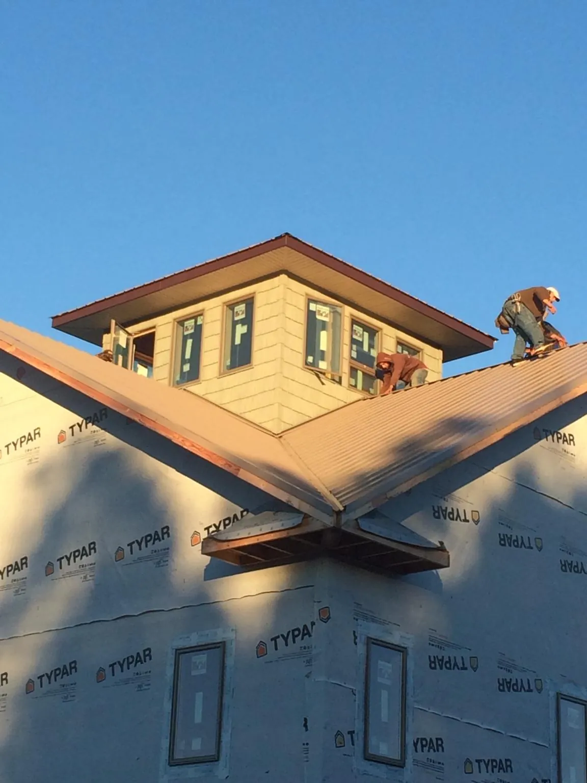 Roofers working around a rooftop cupola on a new metal roof at sunset — Roof Waterproofing in Waldwick by Roofing Brothers
